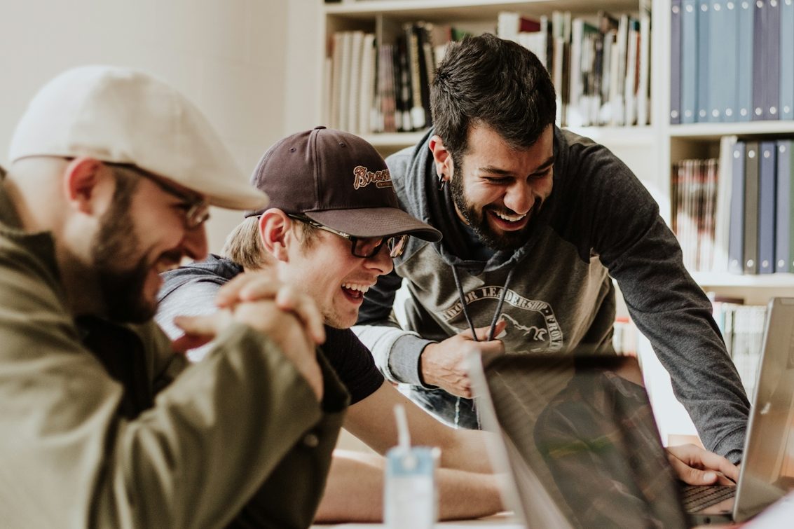 Groep jonge mannen Groep jonge mannen zit op zitzakken met laptops, bezig met hun werk.